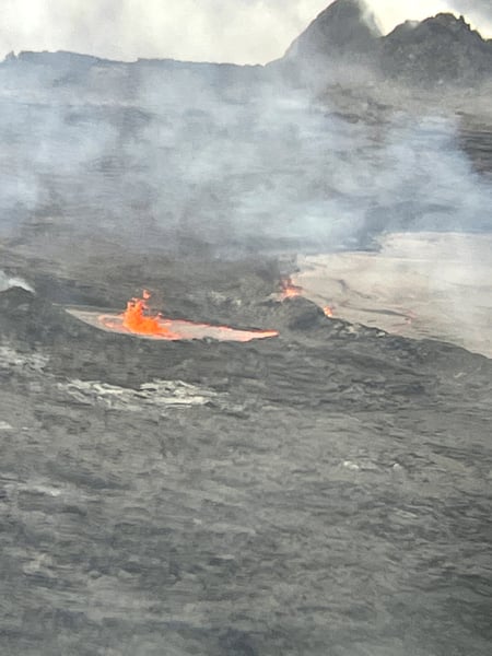 Active lava flow from volcanic crater with steam and smoke rising from the crater rim, photographed from volcanic… — Hawaiʻi Volcanoes National Park, Big Island, Hawaii