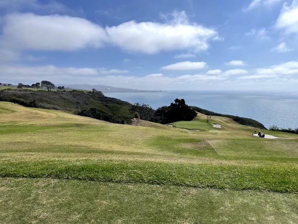Coastal golf course with manicured greens overlooking the Pacific Ocean, viewed from the fairway. — San Diego