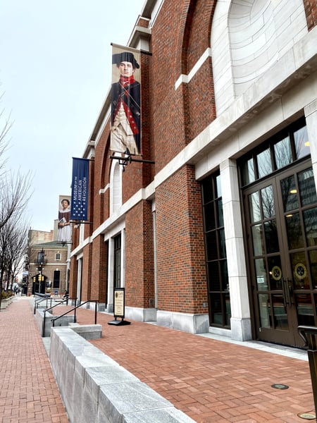 Historic brick building with colonial-era mural and banner displayed on facade, viewed from street-level plaza. — Center City, Philadelphia