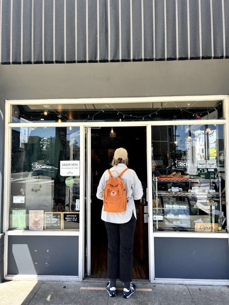 A visitor enters The Richfield storefront on San Francisco's 5th Avenue with an orange backpack. — Inner Richmond, San Francisco