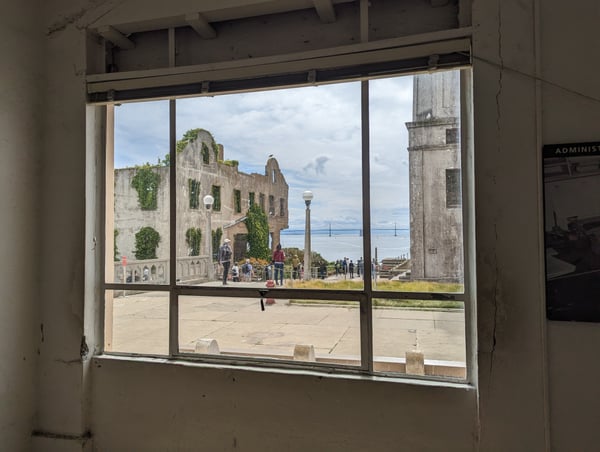 View of Alcatraz Main Cell House and courtyard with Golden Gate Bridge visible in the distance, seen through an… — Alcatraz Main Cell House, San Francisco
