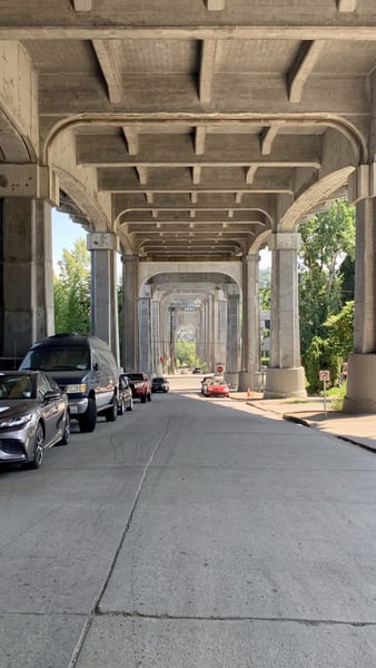 Underpass of the Fremont Bridge with concrete support columns and arches, viewed from street level with parked vehicles. — Seattle
