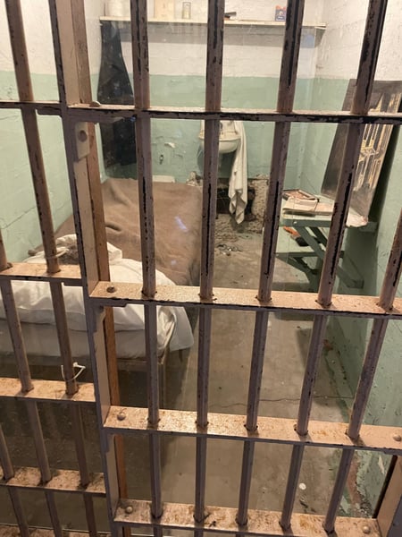 View through a prison cell door at Alcatraz Main Cell House, showing a sparse cell with basic furnishings and… — Alcatraz Main Cell House, San Francisco