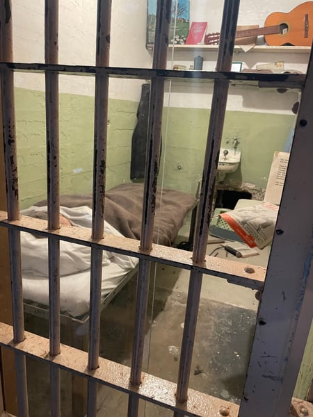 Historic prison cell at Alcatraz Main Cell House viewed through barred door, showing period furnishings and… — Alcatraz Main Cell House, San Francisco