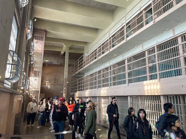 Tourists touring the main cell block at Alcatraz Federal Penitentiary with multi-tiered prison cells visible. — Alcatraz Main Cell House, San Francisco