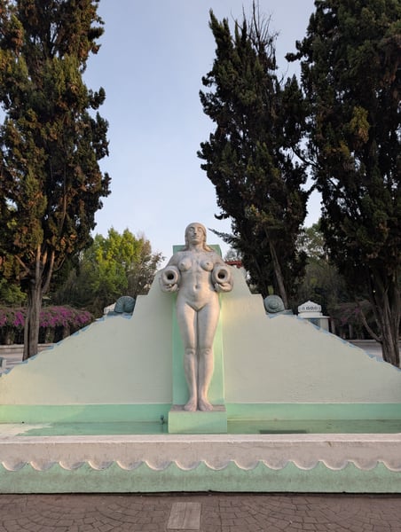 Monumental female sculpture with vessel holders in a landscaped plaza lined with tall cypress trees in Mexico City. — Condesa, Mexico City