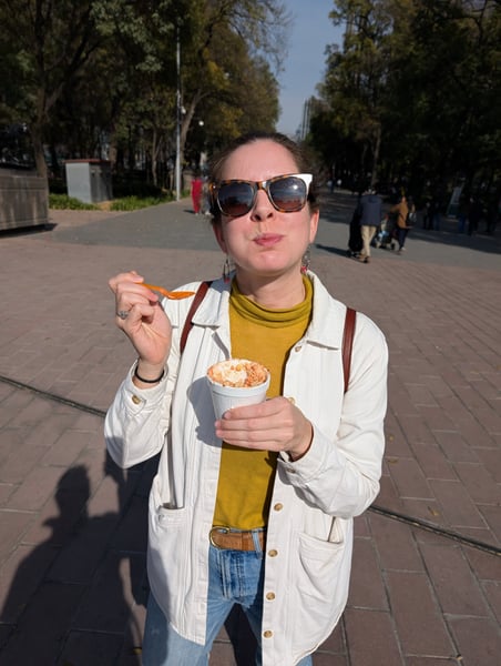 Woman enjoying street food in an urban plaza lined with tall trees in Mexico City. — San Miguel Chapultepec, Mexico City
