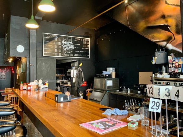 Interior of Bare Bones café and bar in Portland, viewed from the customer seating area at the wooden counter. — Buckman, Portland