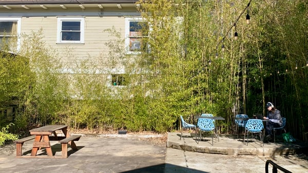 A small urban courtyard with seating areas, bamboo screening, and a residential building in Portland, Oregon. — Central Eastside, Portland