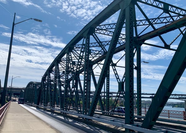 Historic steel truss bridge with green metalwork viewed from pedestrian walkway above water. — Hawthorne Bridge, Portland