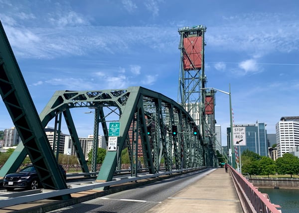 Historic steel truss bridge with vertical lift tower spanning a river, viewed from the pedestrian walkway with downtown… — Hawthorne Bridge, Portland