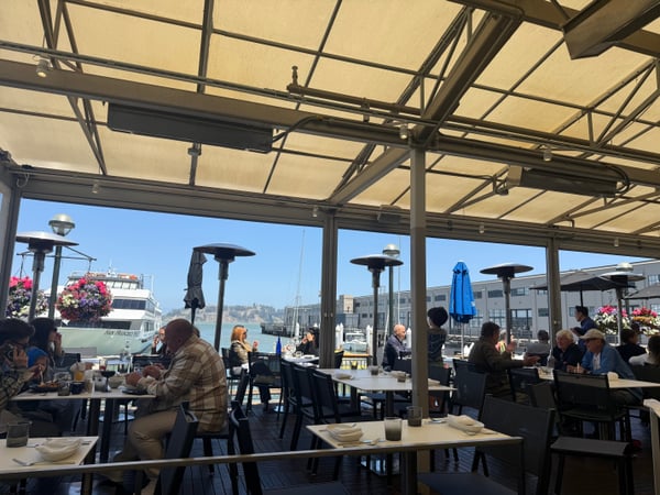 Waterfront dining at a covered outdoor café with marina views and sailboats visible in the background. — Financial District, San Francisco