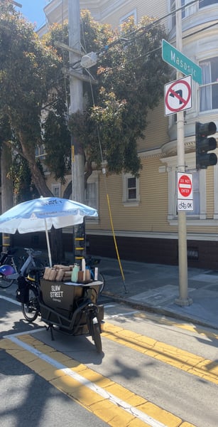 A mobile coffee cart with branded umbrella on Mason Street in San Francisco, with historic Victorian architecture and… — Haight-Ashbury, San Francisco