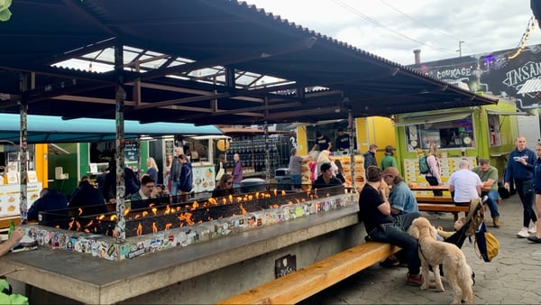 Outdoor food market with colorful vendor stalls, communal seating, and a fire pit attraction in Portland, Oregon. — Hosford-Abernethy, Portland