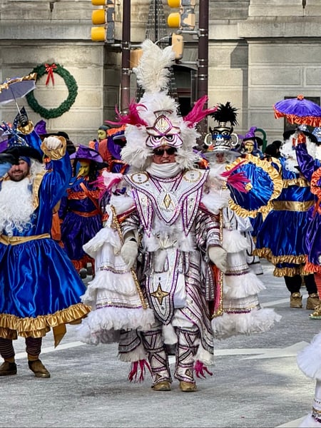 Mardi Gras parade participants in elaborate white and purple costumes with feathered headdresses parade down a… — Center City, Philadelphia