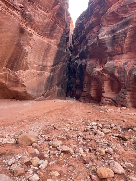 Narrow slot canyon with towering red sandstone walls and hikers on the canyon floor near Kanab, Utah. — The Wave Trail, Kanab & The Wave
