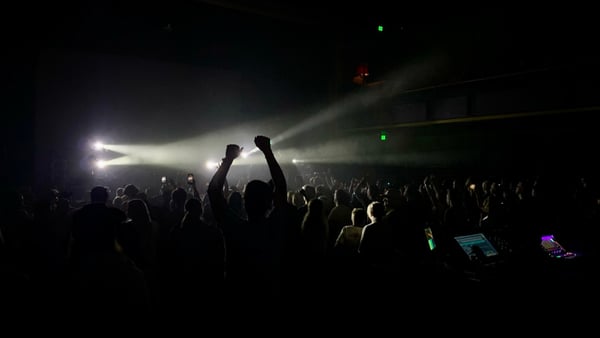 Large crowd at an indoor concert venue with stage lighting and raised fists during a live music performance. — Portland