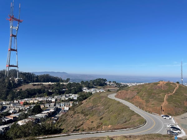 Twin Peaks overlook with winding road, communication tower, and San Francisco Bay vista in the distance. — Midtown Terrace, San Francisco