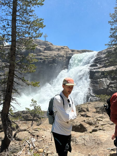 A hiker at a viewpoint overlooking a powerful cascading waterfall in the Sierra Nevada mountains during spring runoff. — Yosemite National Park