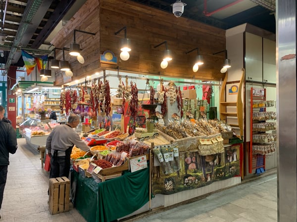 Traditional Italian market stall displaying cured meats, dried peppers, and local specialties in an indoor market hall… — Florence