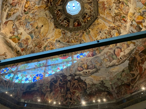 Interior dome with Renaissance frescoes and stained glass light streaming through an octagonal cupola in Florence…