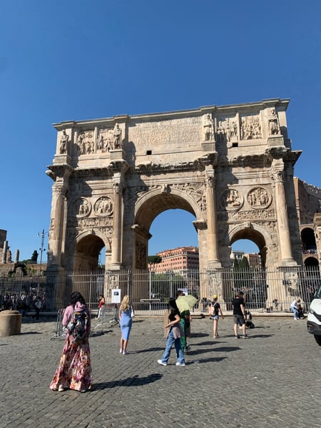 Ancient Roman triumphal arch with ornate sculptural reliefs and three barrel vaults, viewed from a public plaza with… — Campitelli, Rome